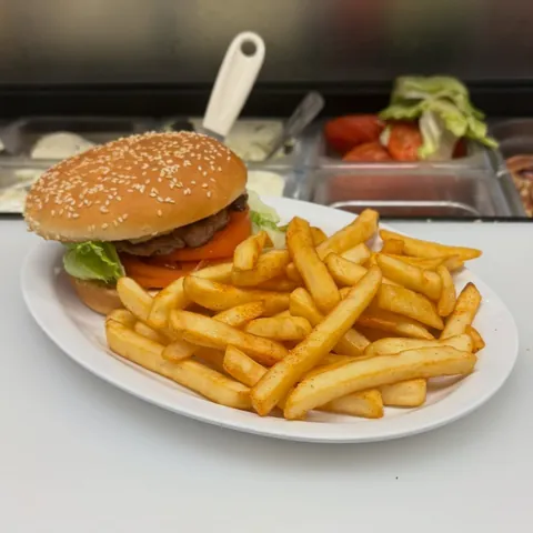Cheeseburger with lettuce and tomato and a pile of seasoned fries