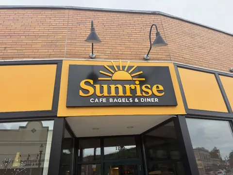 The Sunrise Cafe Bagels and Diner storefront sign in gold and black on River Street